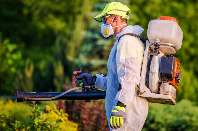 Pest control technician with backpack sprayer in outdoor area
